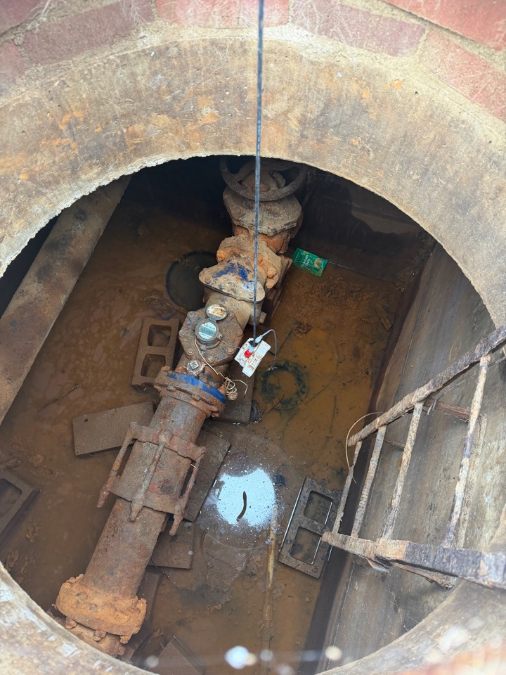 Looking down a vault ladder at a backflow assembly