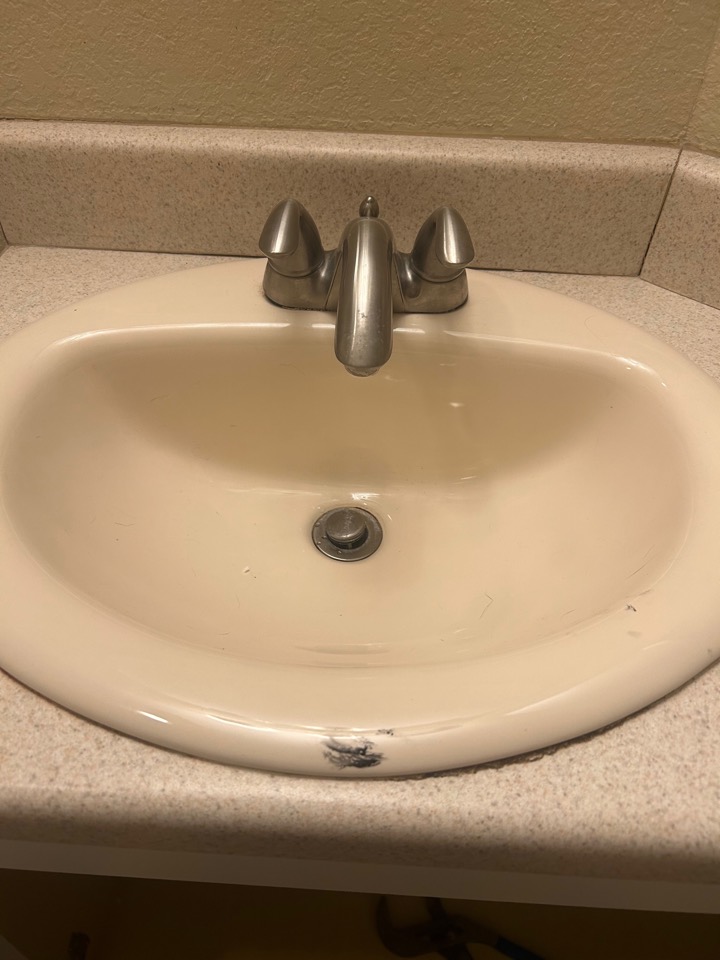 An old bathroom sink faucet before replacement