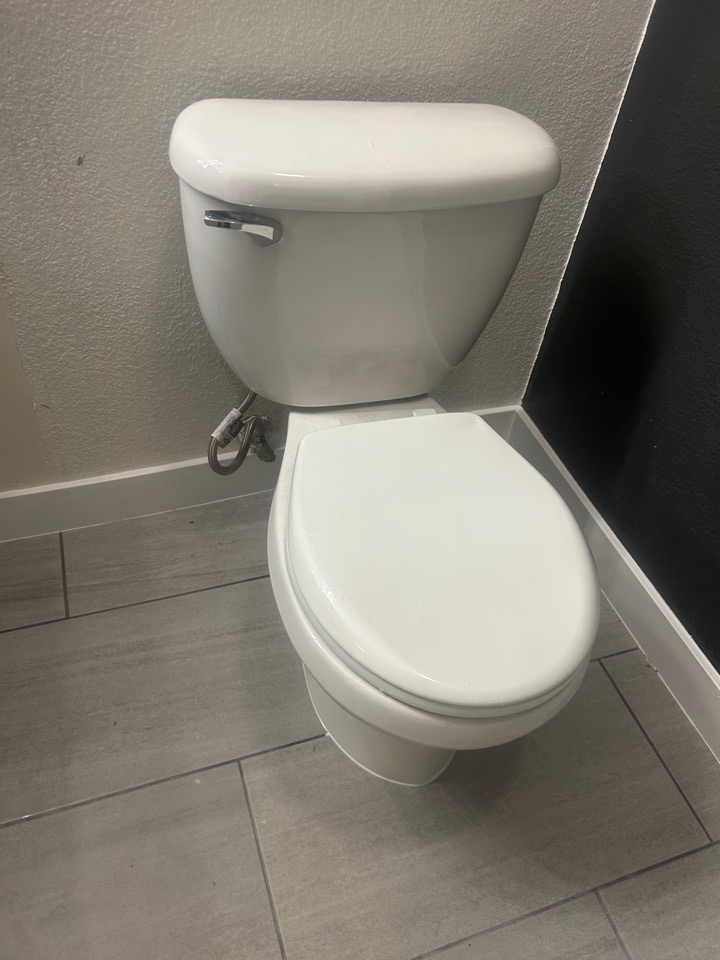 A newly installed white toilet on a gray tile floor