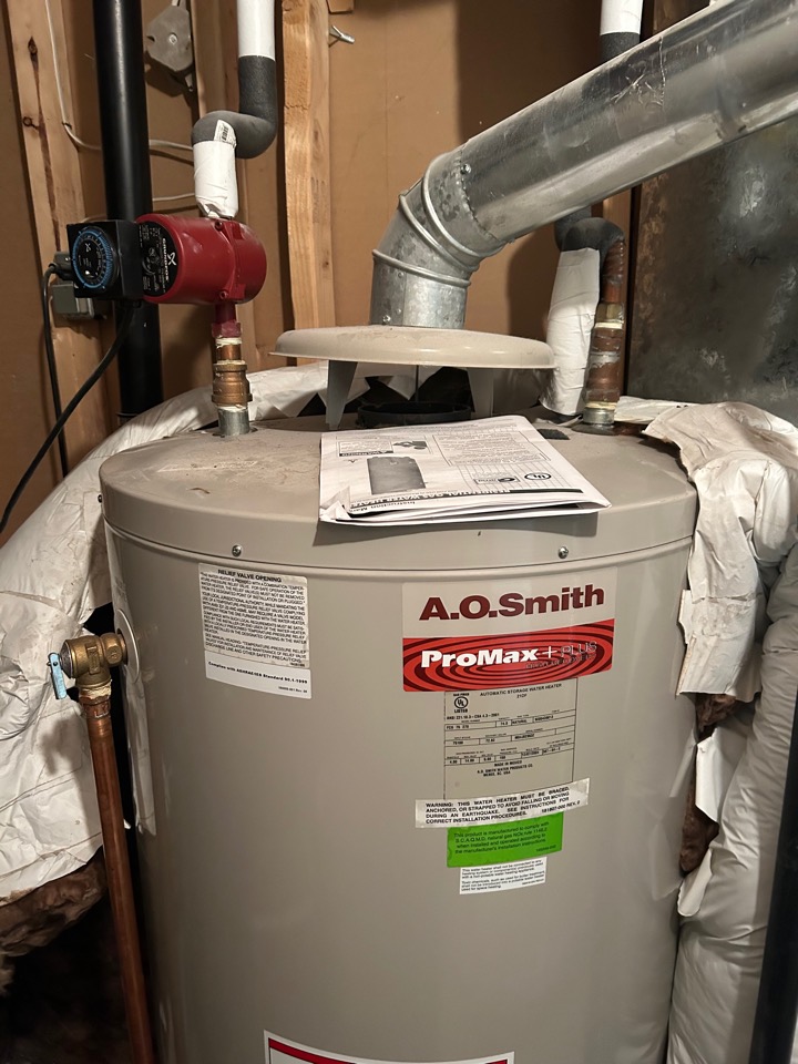 A new A.O. Smith ProMax water heater with its vent and a recirculation pump connected, the manual still on top